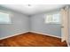 Bedroom with hardwood floors, ceiling fan, light-blue walls, two windows, and white baseboards at 117 Castlerock Dr, Durham, NC 27713