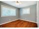 Bedroom with hardwood floors, ceiling fan, light-blue walls, two windows, and white baseboards at 117 Castlerock Dr, Durham, NC 27713
