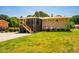 Spacious brick home featuring a screened-in porch, lush green lawn, and mature trees under a bright blue sky at 117 Castlerock Dr, Durham, NC 27713