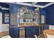 Close-up of bar with blue cabinets, wood countertop, brass fixtures, and mirrored glass shelving at 117 Queensferry Rd, Cary, NC 27511