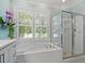 Bathroom featuring a separate shower, soaking tub, and plantation shutters for natural light at 12527 Bellstone Ln, Raleigh, NC 27614