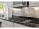 Close-up of modern gas range, stainless steel appliances, tile backsplash, and granite countertops in updated kitchen at 12527 Bellstone Ln, Raleigh, NC 27614