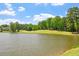 Scenic lakeside view of a well-manicured golf course with mature trees under a blue sky at 12527 Bellstone Ln, Raleigh, NC 27614