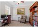 Home office with traditional decor, featuring a large wooden bookcase, plush chair, and elegant artwork at 12527 Bellstone Ln, Raleigh, NC 27614