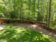 Large grassy backyard with a wooded area behind a brown wooden fence at 12537 Birchfalls Dr, Raleigh, NC 27614