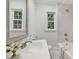 Bright bathroom featuring a white vanity, a large mirror, and a bathtub with tiled walls at 1316 Glenwood Ave, Raleigh, NC 27605