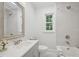 Bright bathroom featuring a tub with tiled shower, white cabinets, and a window at 1316 Glenwood Ave, Raleigh, NC 27605