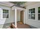 Inviting front porch with classic wooden door, flanked by bright, sunlit windows, creating a warm welcome at 1316 Glenwood Ave, Raleigh, NC 27605