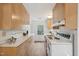 Galley kitchen featuring light wood cabinets, white countertops, modern flooring and stainless steel sink at 1316 Glenwood Ave, Raleigh, NC 27605
