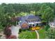Aerial view of brick estate home surrounded by beautiful landscaping, a dense forest and a nearby golf course at 1501 Samuel Wait Ln, Wake Forest, NC 27587