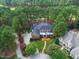 Aerial view of beautiful estate home surrounded by a dense forest, lush landscaping, and colorful flower beds at 1501 Samuel Wait Ln, Wake Forest, NC 27587