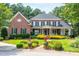Stately brick home features a covered porch, lush landscaping, and manicured lawn at 1501 Samuel Wait Ln, Wake Forest, NC 27587