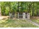 Quaint wooden chicken coop in a lush, tree-filled backyard with brick paver path and chair at 170 Homestead Rd, Angier, NC 27501
