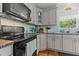 A quaint kitchen featuring grey cabinets, a black range oven, and a window overlooking the outdoors at 170 Homestead Rd, Angier, NC 27501