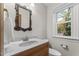 Updated bathroom featuring a granite vanity top, decorative mirror, and natural light from the window at 1705 Bridgeport Dr, Raleigh, NC 27615