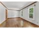 Bedroom featuring hardwood floors, white trim, large windows, and a neutral color palette at 1705 Bridgeport Dr, Raleigh, NC 27615