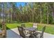 Outdoor patio with a table and chairs overlooking a vast backyard filled with trees and green grass at 1840 Willie Pace Rd, Burlington, NC 27217