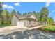 Side view of a single-story gray home, showcasing the driveway and an attached garage, surrounded by mature trees at 1840 Willie Pace Rd, Burlington, NC 27217