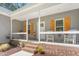 Cozy front porch with seating, white railing, and brick accents, enhanced by the surrounding lush greenery at 1840 Willie Pace Rd, Burlington, NC 27217