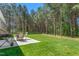 Outdoor patio with a grill and a table and chairs overlooking a vast backyard filled with trees and green grass at 1840 Willie Pace Rd, Burlington, NC 27217
