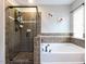 Tiled bathroom featuring a glass-enclosed shower, separate soaking tub, and a window at 1909 Whirlaway Ct., Cary, NC 27519