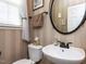 Stylish half bathroom featuring modern fixtures, wallpaper, an oval mirror, and natural light from a window at 1909 Whirlaway Ct., Cary, NC 27519
