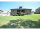 Rear view of a brick home with a screened porch, landscaped yard, and mature trees in the background at 197 W Paige Wynd Dr, Angier, NC 27501