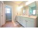 This bathroom features double sinks, white cabinets, two mirrors, light green walls and tiled floors at 197 W Paige Wynd Dr, Angier, NC 27501