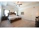 This main bedroom has a large bed, carpeted floors, decorative art and a tray ceiling with ceiling fan at 197 W Paige Wynd Dr, Angier, NC 27501