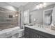 Bright bathroom with tile surround tub/shower, marble counters and a large mirror at 209 Preston Retreat Ln, Cary, NC 27513