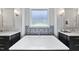 Luxurious soaking tub centered between dual vanities with a decorative tile backsplash and modern fixtures at 209 Preston Retreat Ln, Cary, NC 27513
