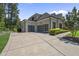Spacious three-car garage with modern glass doors and a paved driveway, surrounded by manicured bushes at 209 Preston Retreat Ln, Cary, NC 27513