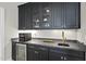 Modern wet bar with dark cabinets, granite countertop, and stainless-steel appliances for entertaining guests at 209 Preston Retreat Ln, Cary, NC 27513