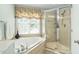 Bathroom features a glass shower and jacuzzi tub under a window at 210 Presidents Walk Ln, Cary, NC 27519