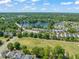 Expansive aerial view showcasing a lush green golf course, lake, and tree-lined residential community at 2105 Metacomet Way, Raleigh, NC 27604