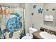 A cozy bathroom featuring sea turtle decor, patterned shower curtain, and essential amenities at 215 Collins Rd, Lillington, NC 27546