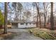 A beautifully renovated one-story home showcasing a crisp white exterior and a spacious driveway surrounded by mature trees at 2224 Clements Dr, Durham, NC 27704
