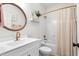 Bright bathroom boasts gold fixtures, a large round mirror, and a shower with beige curtain at 2775 Eagles Roost Trl, Burlington, NC 27217