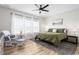 Calm primary bedroom features a ceiling fan, many windows with white curtains, and cozy furniture at 2775 Eagles Roost Trl, Burlington, NC 27217