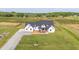 Exterior aerial view of modern farmhouse with porch, gravel driveway, and spacious, landscaped yard at 2775 Eagles Roost Trl, Burlington, NC 27217