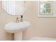 A pedestal sink bathroom featuring a mirror and a window with natural light at 300 Sugar Maple Ave, Wake Forest, NC 27587