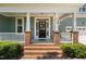 Welcoming porch with brick accents leads to a charming home with a beautifully adorned front door at 304 Nelson Ln, Clayton, NC 27527