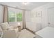 Well-lit Bedroom featuring a white crib, comfortable chair, neutral paint, and large windows at 3113 Chelmshire Ct, Raleigh, NC 27610