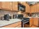 Close-up of a kitchen featuring granite countertops, a gas range, and wooden cabinets at 3633 Willow Stone Ln, Wake Forest, NC 27587