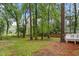 Spacious backyard with mature trees, a grassy lawn, and a deck area at 3907 Inwood Dr, Durham, NC 27705