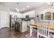 Bright kitchen featuring white cabinets, stainless steel appliances, a granite island, and a dining area with wood floors at 420 Cherry St, Fuquay Varina, NC 27526