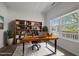 Bright home office featuring a large desk, bookcase and a view of the front yard through a sunlit window at 4805 Ayden Mill Rd, Apex, NC 27539