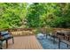Outdoor deck featuring seating, a coffee table, and a view of the lush, mature backyard landscaping at 4900 American Dr, Durham, NC 27705