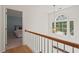 Upstairs hallway with railing and a view into bedroom, enhanced by a statement window and light fixture at 4900 American Dr, Durham, NC 27705