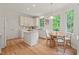 Bright eat-in kitchen with white cabinetry, hardwood floors, and natural light from multiple windows overlooking the yard at 4900 American Dr, Durham, NC 27705